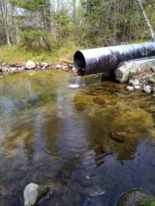 Photo of a large pipe with water running into a pool of water
