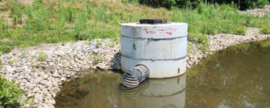 Photo of a large cement cylinder with a tube in a pool of water